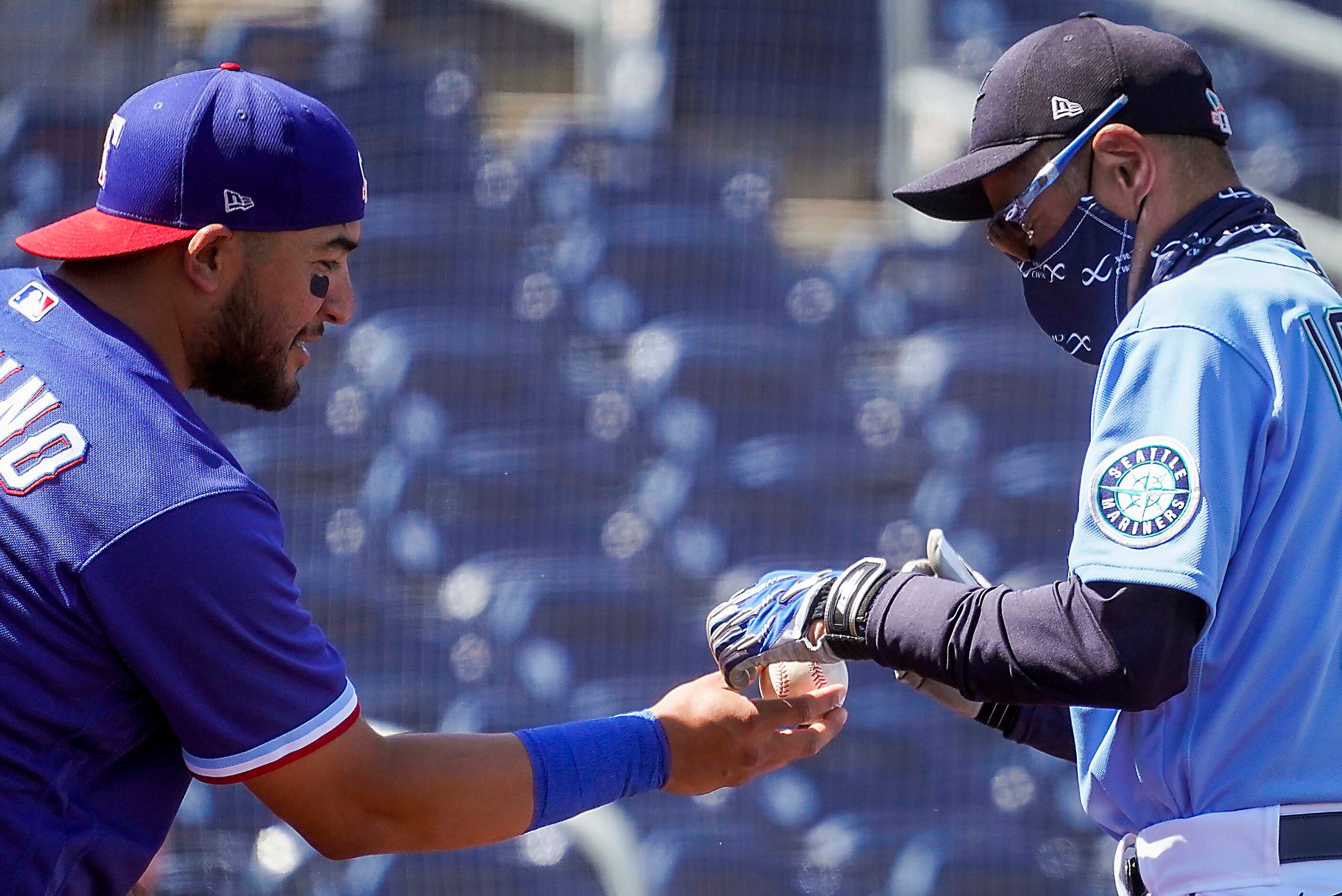 Texas Rangers catcher Jose Trevino hands a ball to Seattle Mariners special assistant to the...