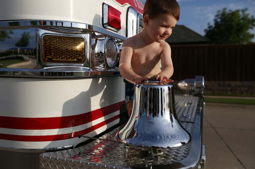 Grayson O'Bryan, 2, stands up after ringing the bell on the front of a Frisco Fire...