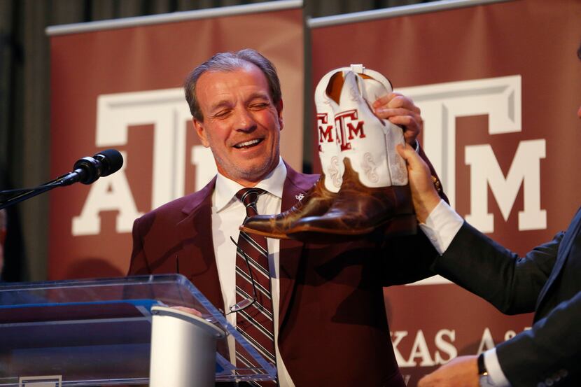 Texas A&M's new coach Jimbo Fisher receives a pair of new boots during a press conference at...