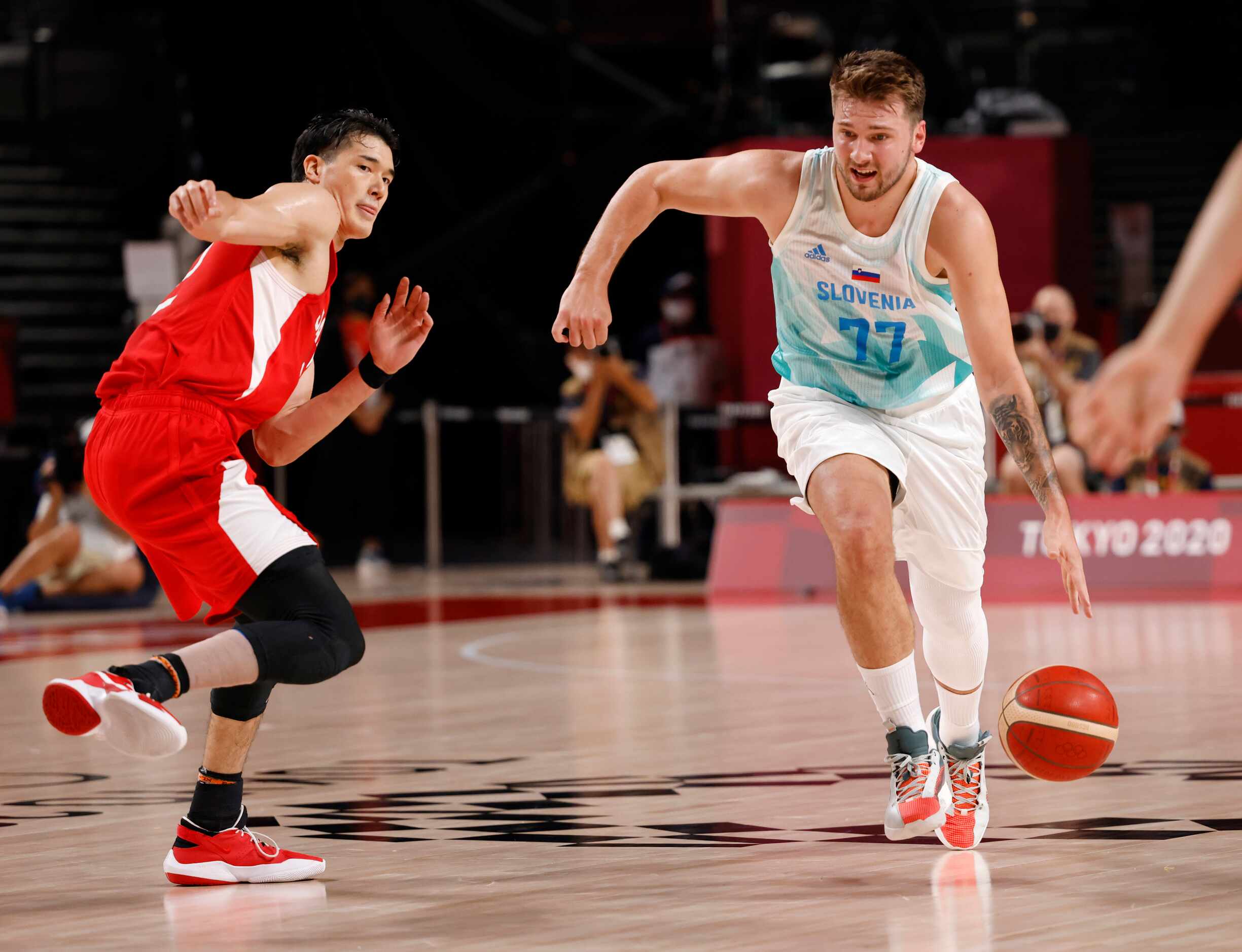 Slovenia’s Luka Doncic (77) drives past Japan’s Yuta Watanabe (12) in a basketball game...