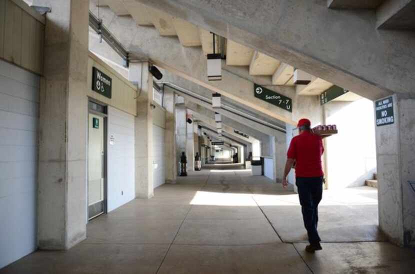Groundskeeper Burt Jones, 71, carries cans of soda through the restrooms and concessions...