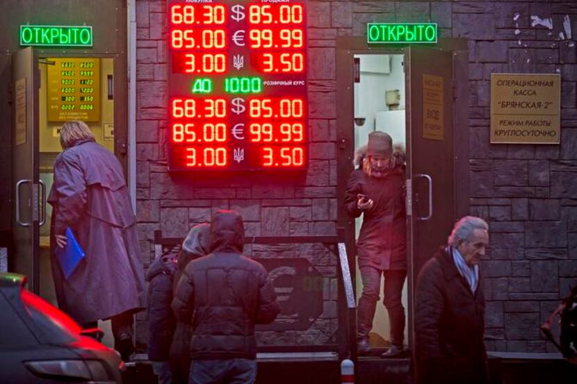 
People exchanged their rubles Tuesday as signs advertised currency exchange rates at an...