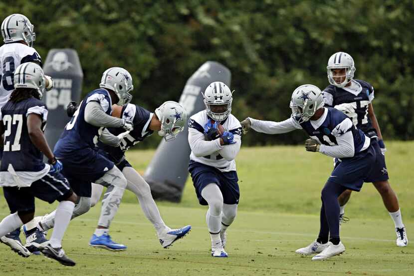 Dallas Cowboys running back Ezekiel Elliott (center) finds a hole during OTA's Wednesday,...