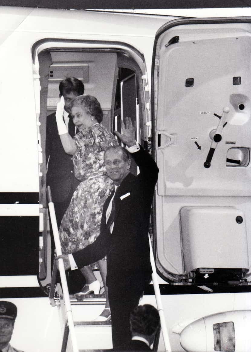 ueen Elizabeth II and Prince Philip wave goodbye as they climb aboard a plane at the end of...