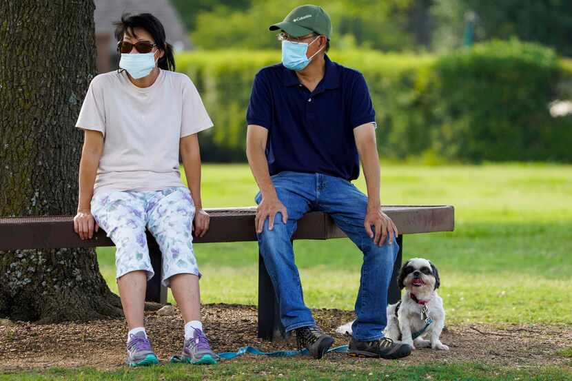 Jeff and Raynette Ho wear face masks as they sit with their dog at Custer Park in Richardson.
