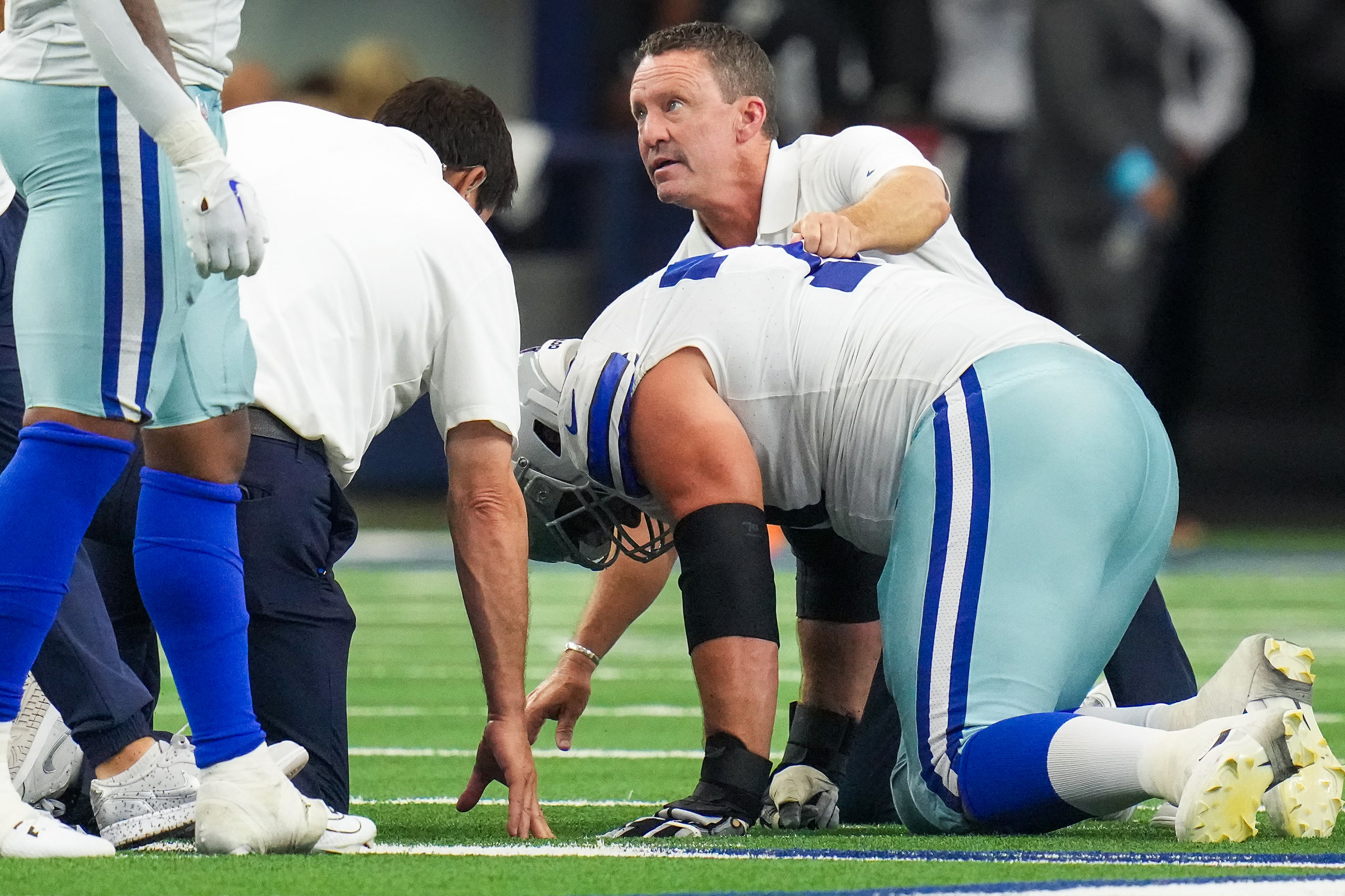 Dallas Cowboys guard Zack Martin is checked on by associate athletic trainer Britt Brown...