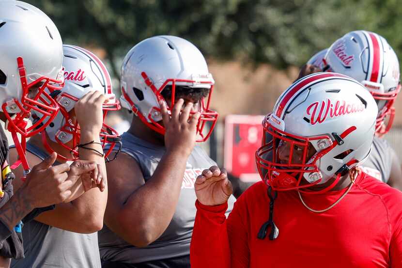 Arnaz Reese (right) signs with fellow deaf student Jabari McGilvery in football practice at...