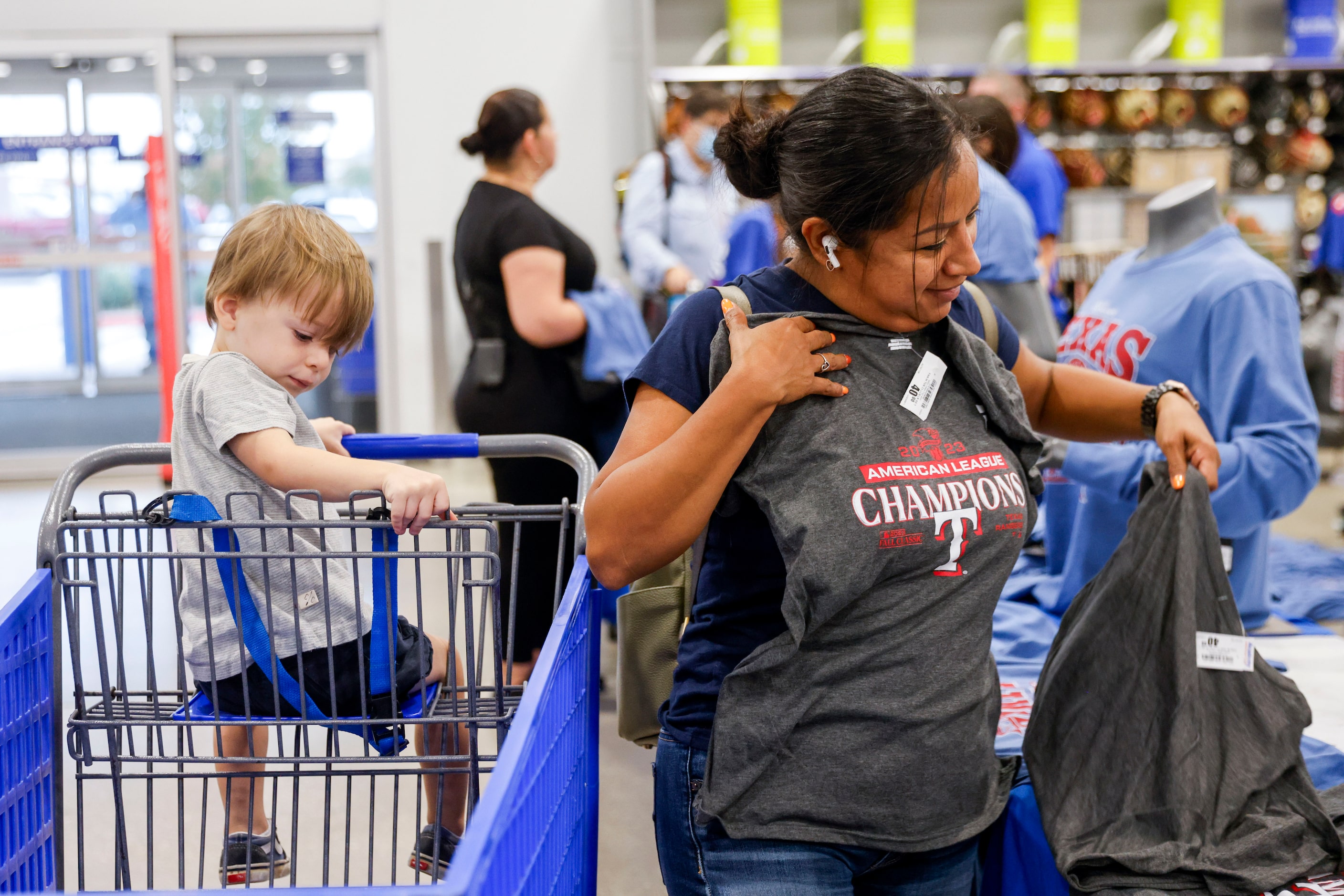 Maria Pecina checks out a Texas Rangers champion theme shirt alongside Shep O’ Harra (left),...