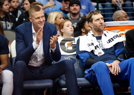 Kristaps Porzingis (left) applauds his teammates while sitting next to Dirk Nowitzki (right)...