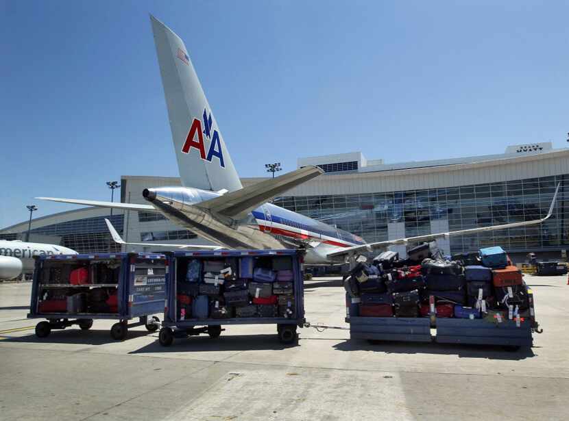 American Airlines luggage sits on the tarmac outside of Terminal D at Dallas/Fort Worth...