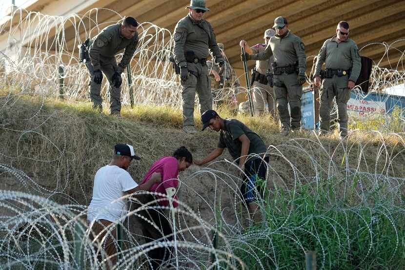 Soldados y guardias de Texas ayudan a una migrante que quedó atrapada en un alambre de púas...