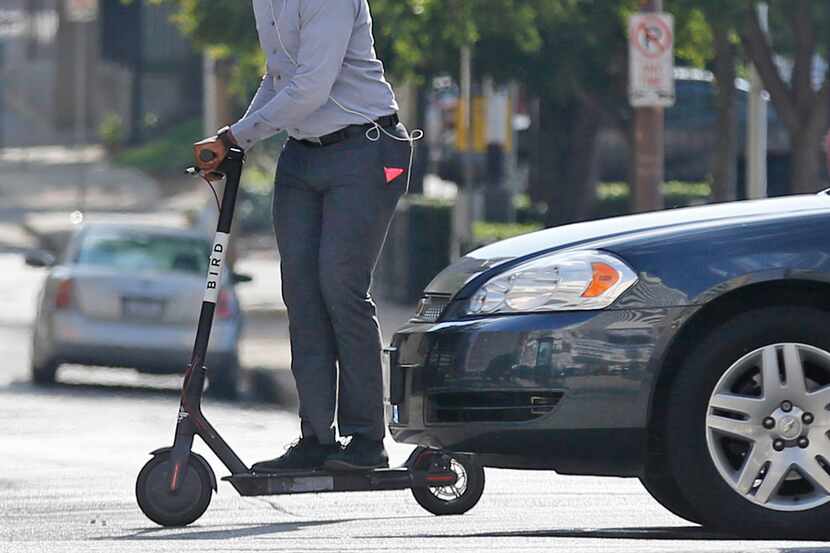 A man on a scooter crosses an intersection in downtown Dallas this month.