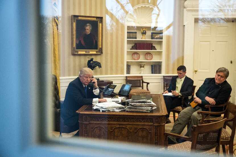 President Donald Trump speaks on the phone as his advisers listen in the Oval Office. (Drew...