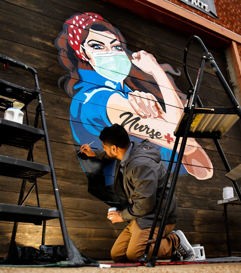 Dallas Artist Miguel Barajas paints a mural of a nurse on the exterior of Redfield's Tavern...