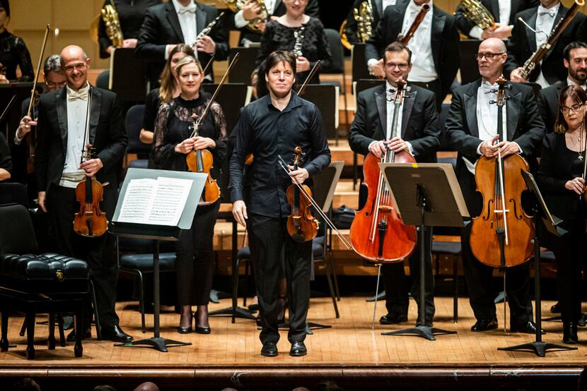 Joshua Bell (center) acknowledges the audience before serving as both the first chair...