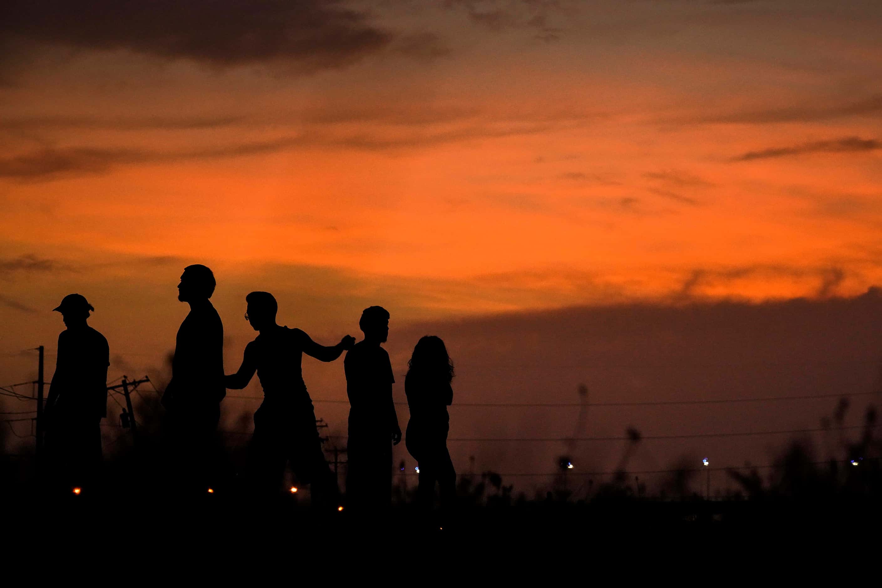 The lingering colors of sunset silhouette young people gathered on the Trinity Skyline Trail...