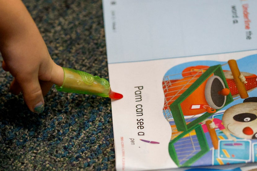 A student points to a word while reading during kindergarten a kindergarten class at...