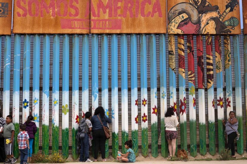 People gather at the U.S. - Mexico border fence to talk to their relatives in Playas de...