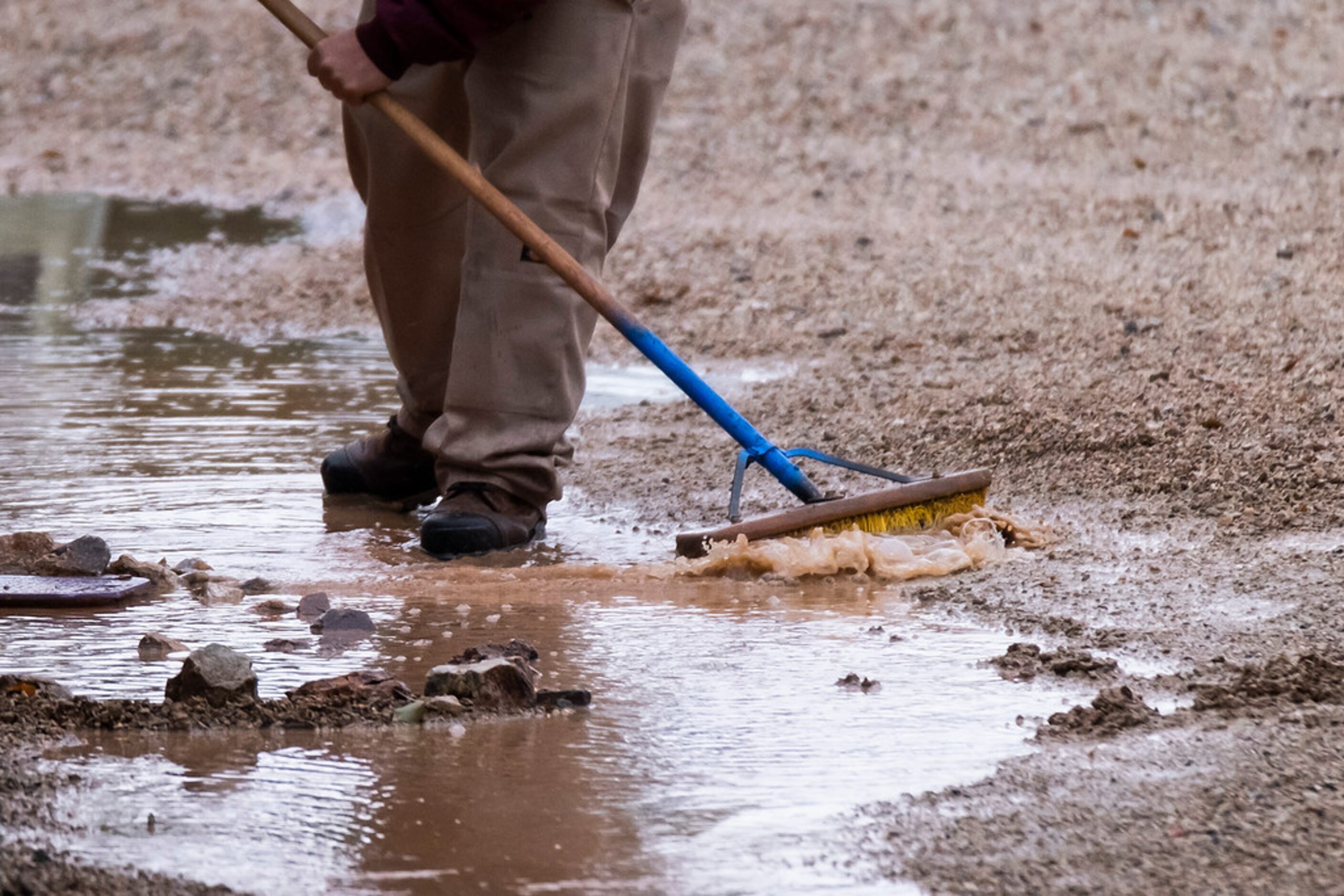 Groundskeepers try to move water toward drains near a practice field before a Texas Rangers...