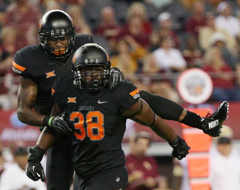 Oklahoma State defensive end Emmanuel Ogbah (38) celebrates with linebacker Josh Furman (14)...