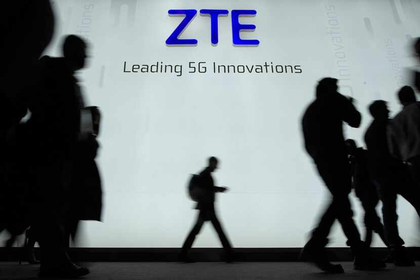 This file picture taken on February 27, 2018 shows people walking in front of the ZTE stand...
