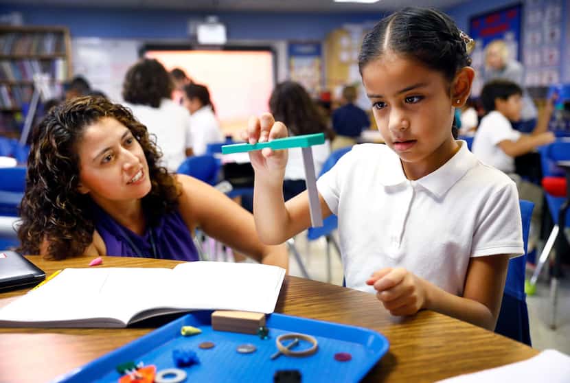Third-grader Jaime Tobon looks at the power of a magnet as her dual language science teacher...