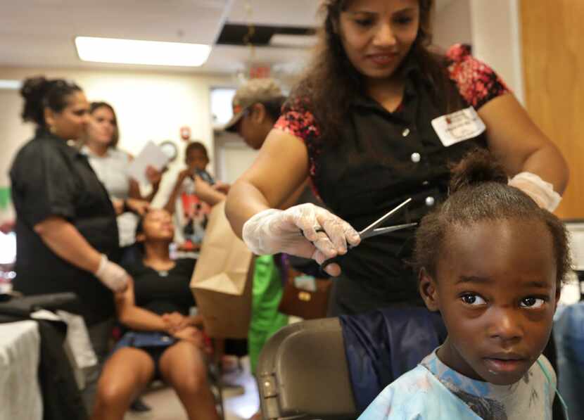 Keyondrea Allen, 4, receives a haircut from Naga Sailaja during the Back2School Fun Fair in...