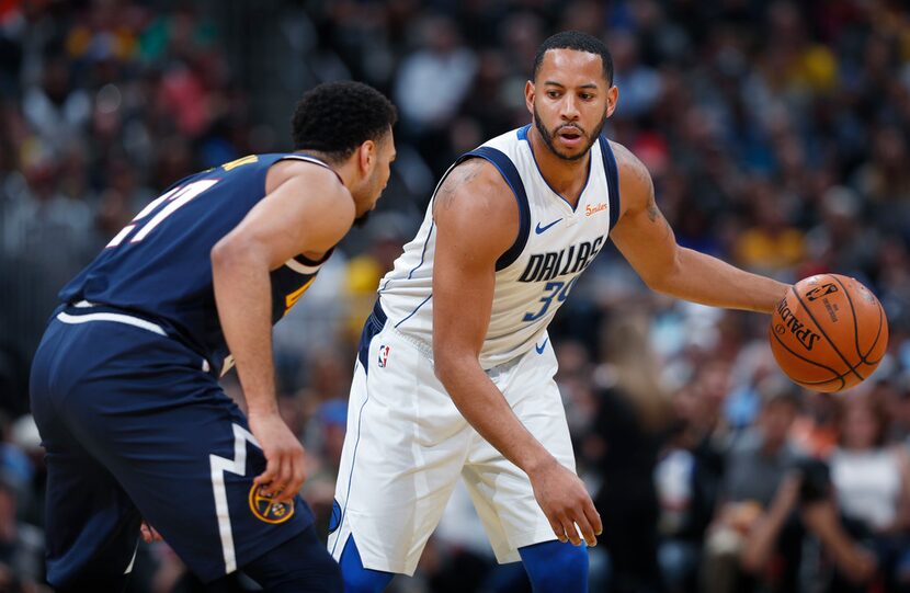 Dallas Mavericks guard Devin Harris, right, looks to pass the ball as Denver Nuggets guard...