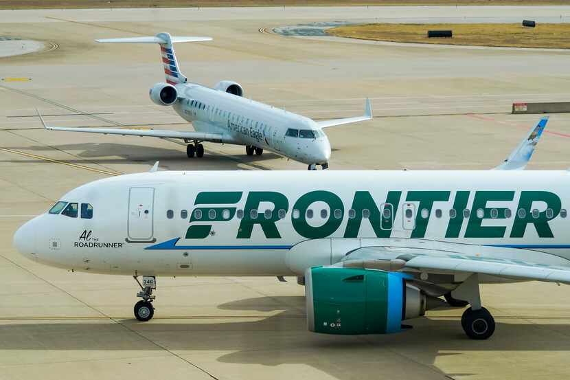 A Frontier Airlines plane taxis past an American Eagle plane near the gates of Terminal E at...