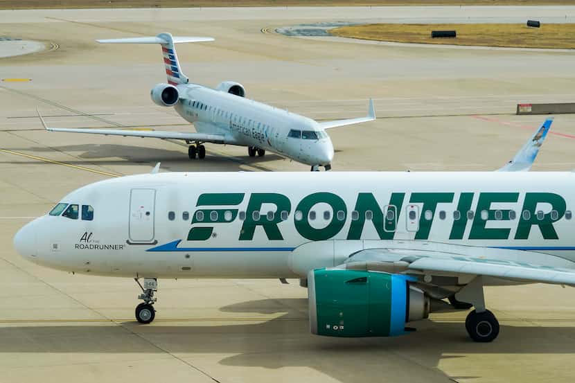 A Frontier Airlines plane taxis past an American Eagle plane near the gates of Terminal E at...