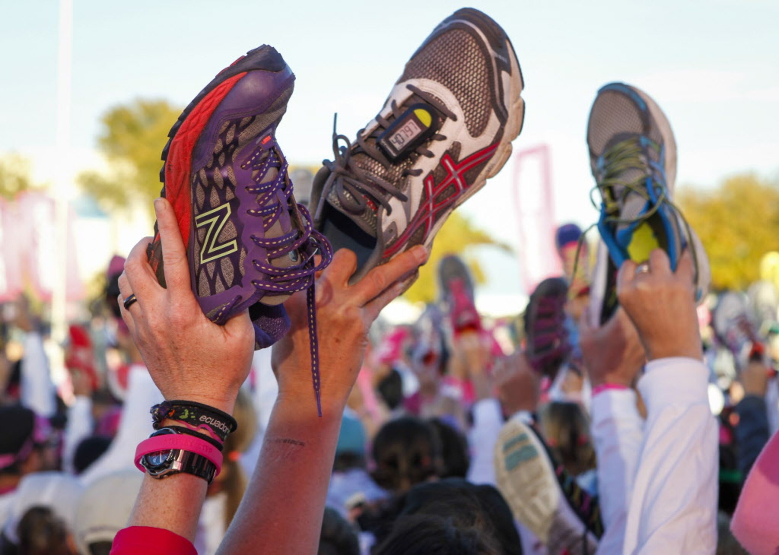 Walkers hold up their shoes in a salute to breast cancer survivors during the closing...