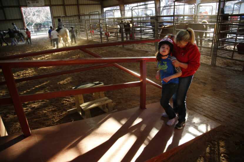 Physical therapist Suzanne Sessums assists Kaitlyn Samuels, 16, on a ramp to a horse at...