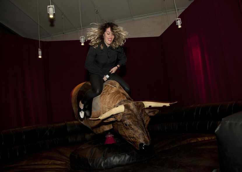 
Sally Glass rides the mechanical bull installed temporarily inside the Nasher Sculpture...