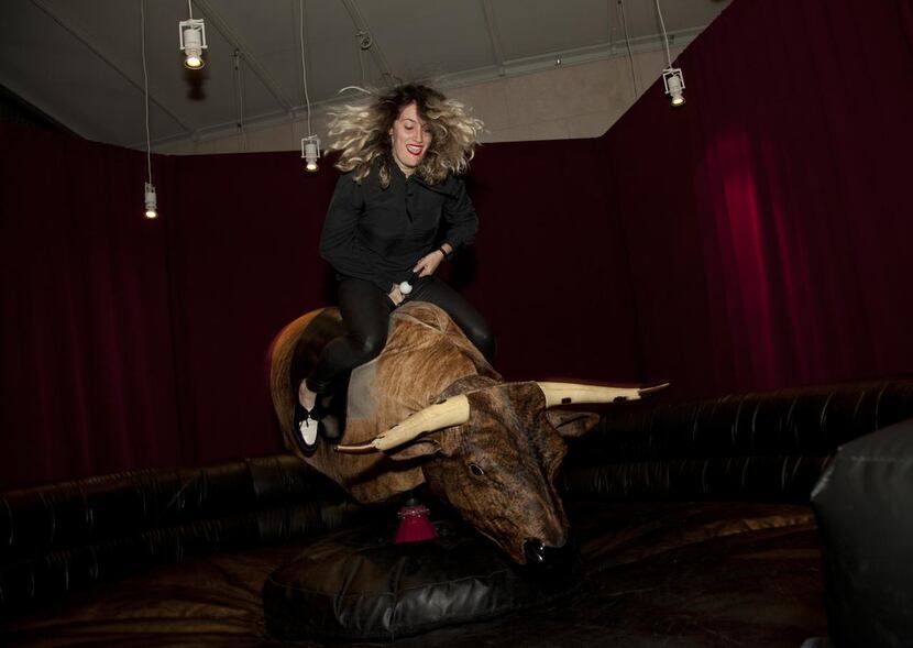 
Sally Glass rides the mechanical bull installed temporarily inside the Nasher Sculpture...