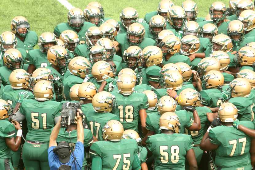 Members of the DeSoto Eagles huddle at midfield during team warm-ups as a videographer from...