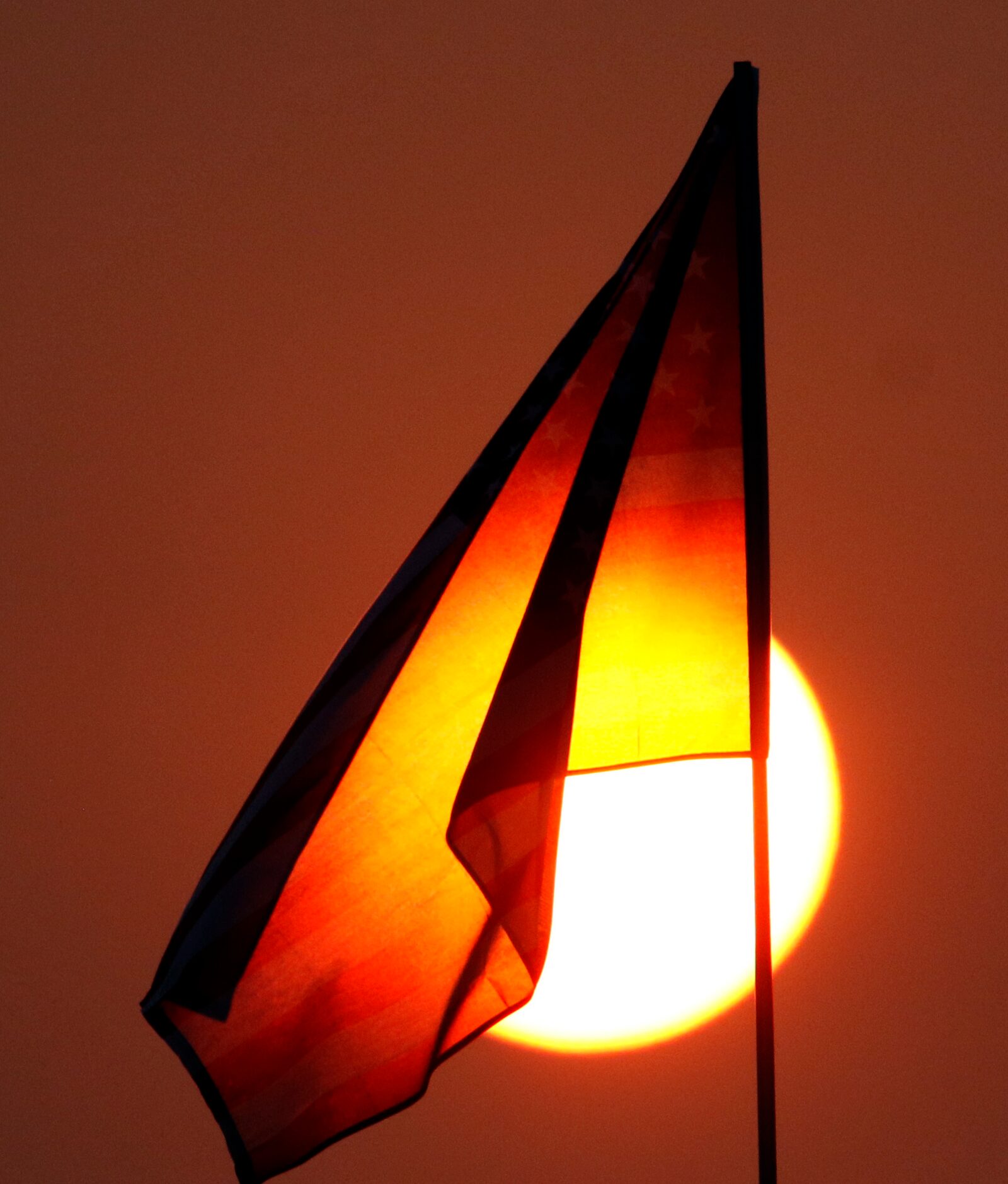 A setting sun illuminates the American flag just prior to the opening kickoff between Argyle...