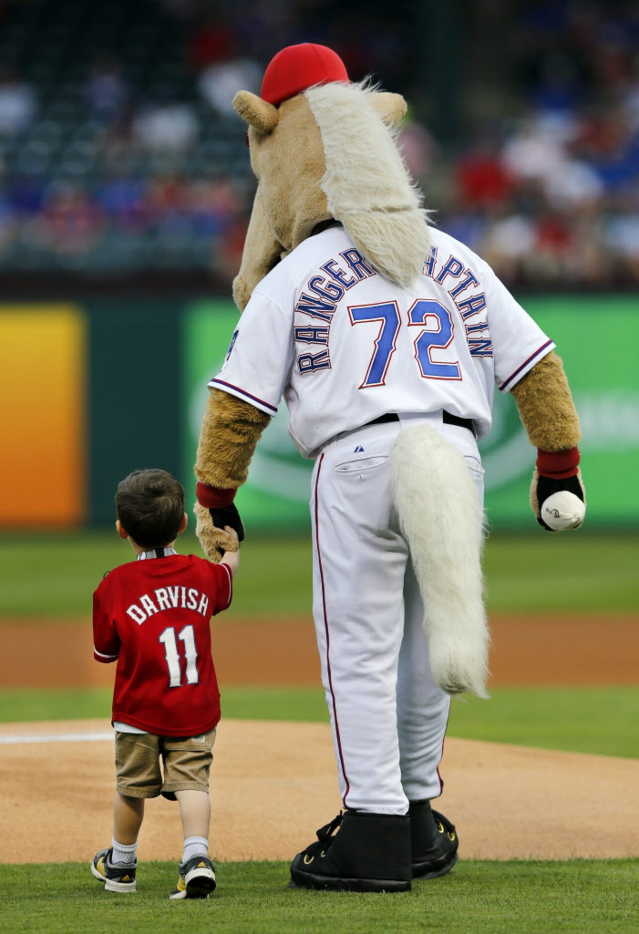 Texas Rangers mascot Captain helps 3 yr-old Keaton lloyd of McKinney deliver the game ball...