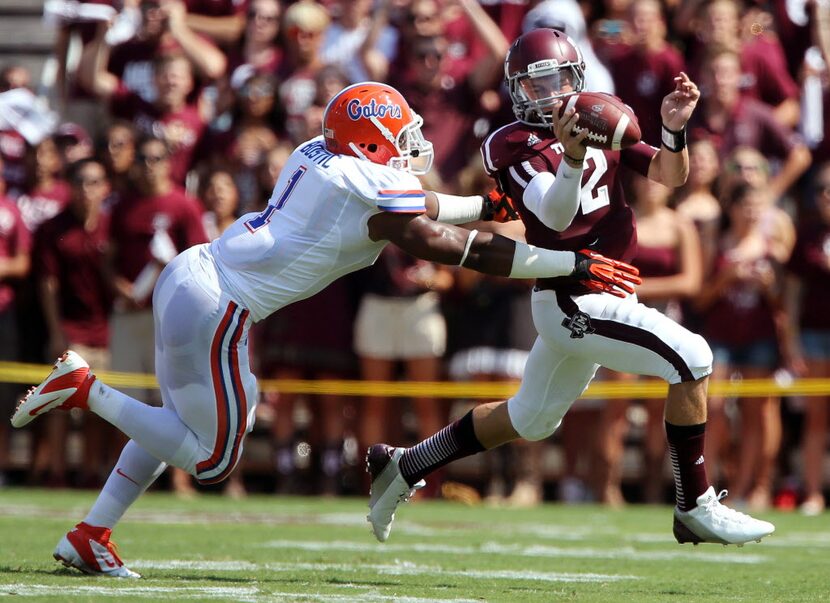 Aggies quarterback Johnny Manziel (2) scrambles away from Florida's Jonathan Bostic (1)...