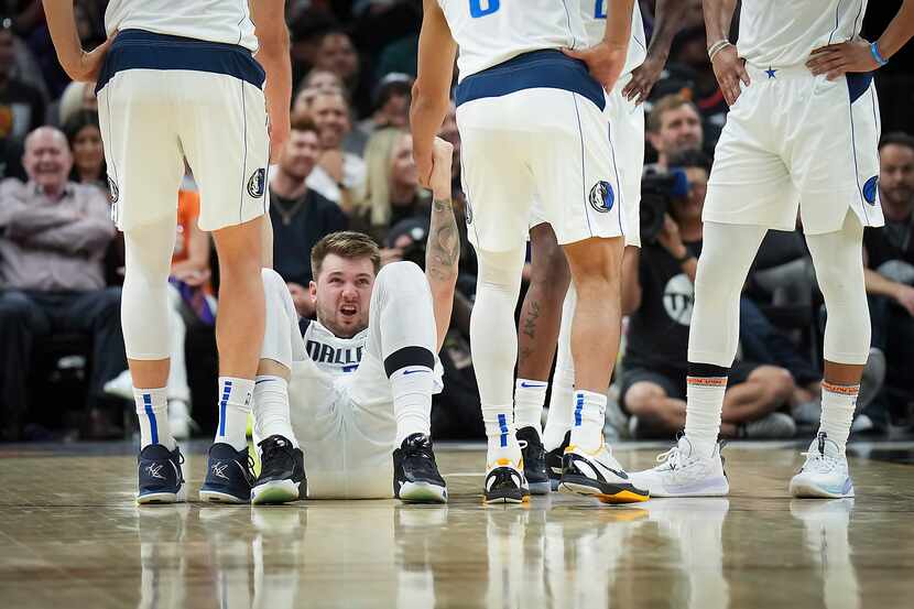 Dallas Mavericks guard Luka Doncic is helped up by teammates after being fouled by Phoenix...