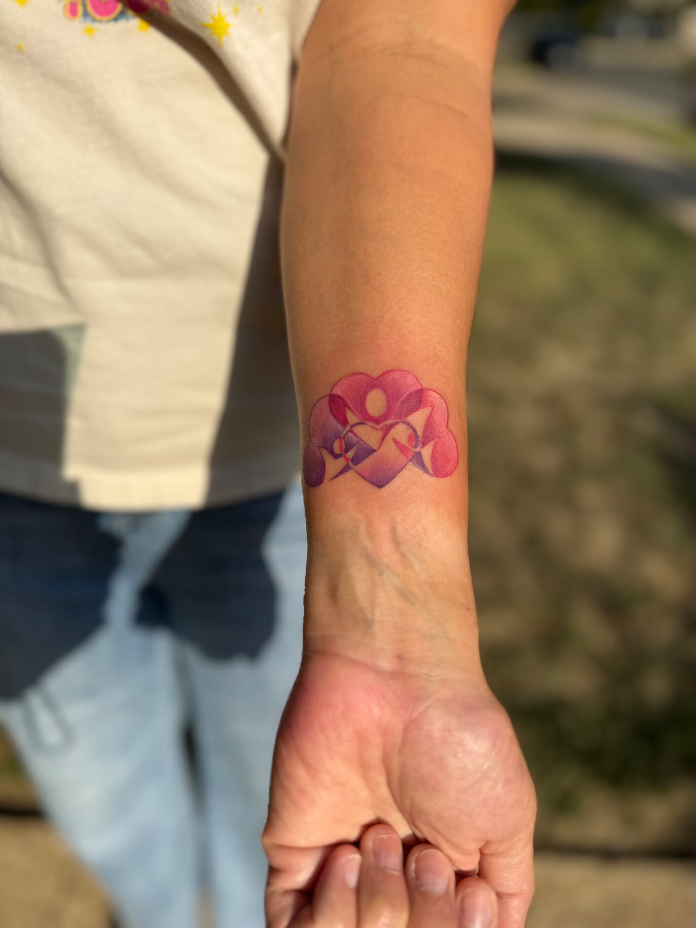 Woman's forearm with a pink and purple tattoo that is a representation of the logo for Nexus...