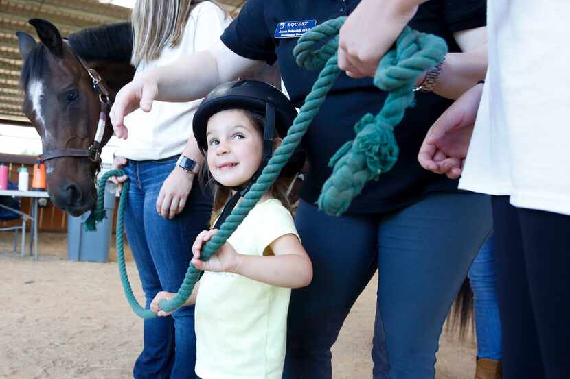 Three-year-old Mora Wolf holds onto her horse's reins as she prepares to lead Hombre back to...