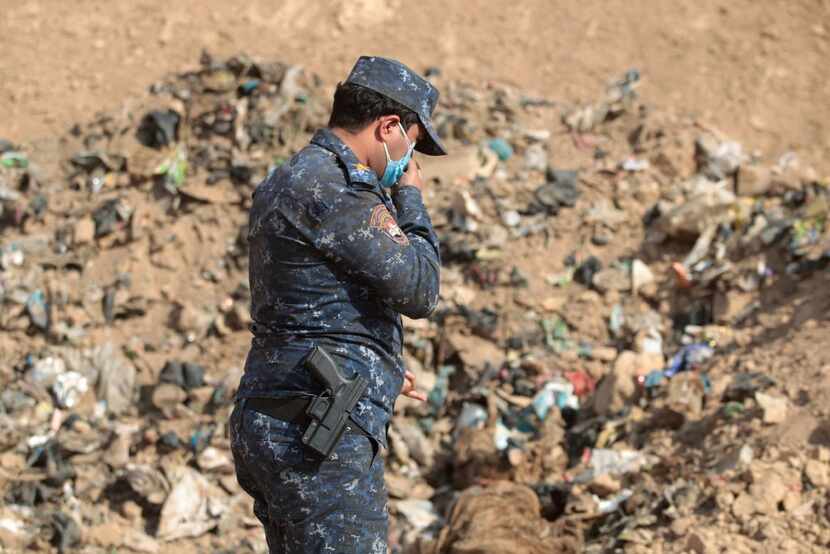 A member of Iraqi security forces checks a mass grave discovered in the Hamam al-Alil area...