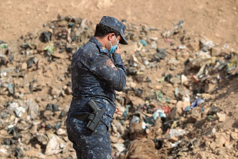 A member of Iraqi security forces checks a mass grave discovered in the Hamam al-Alil area...