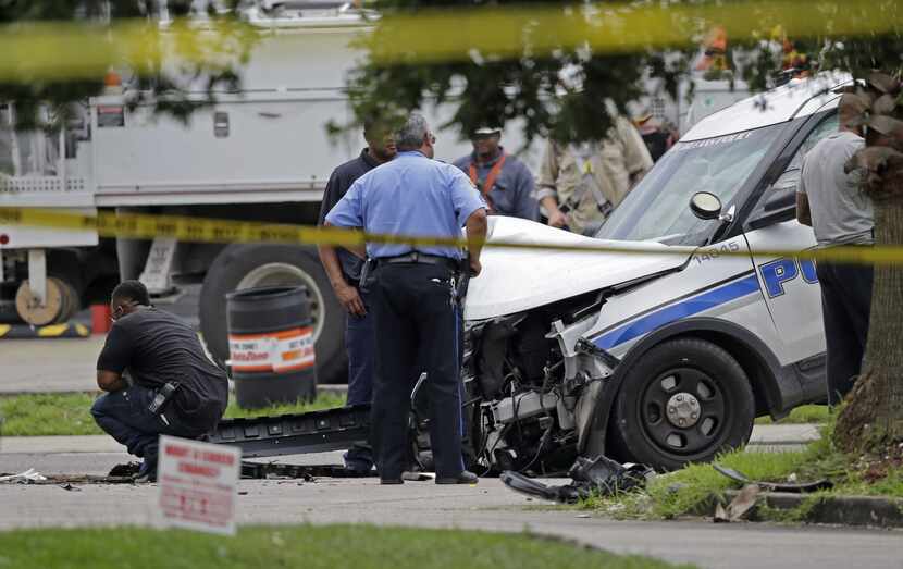 Investigators look over a New Orleans Police department vehicle in which one officer was...