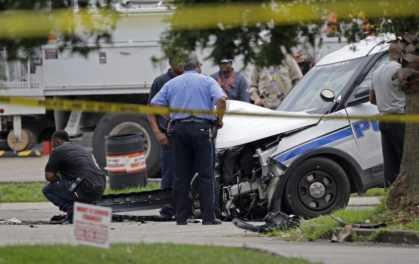 Investigators look over a New Orleans Police department vehicle in which one officer was...