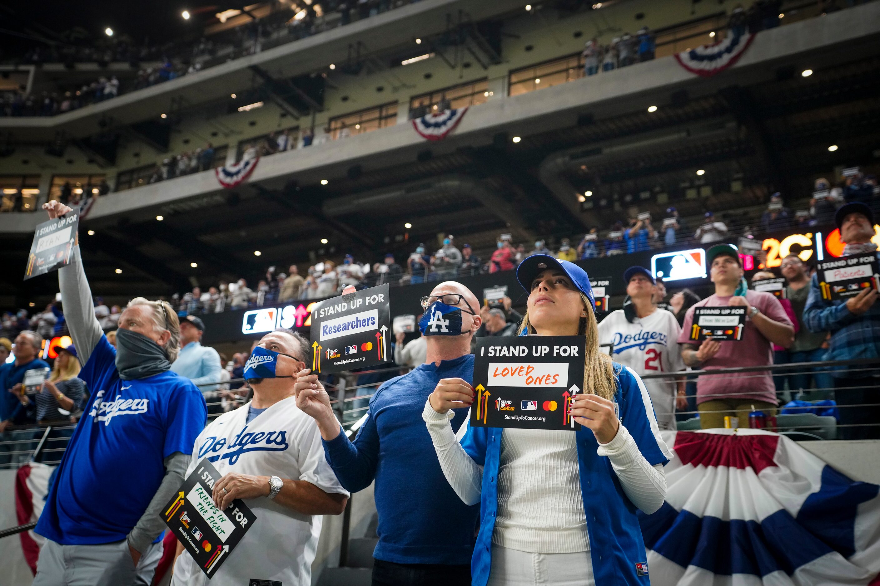 Fans hold up signs as part of the Stand Up To Cancer campaign during the fifth inning in...