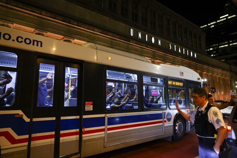 Migrants wave as a bus leaves to take them to a refugee center outside Union Station in...