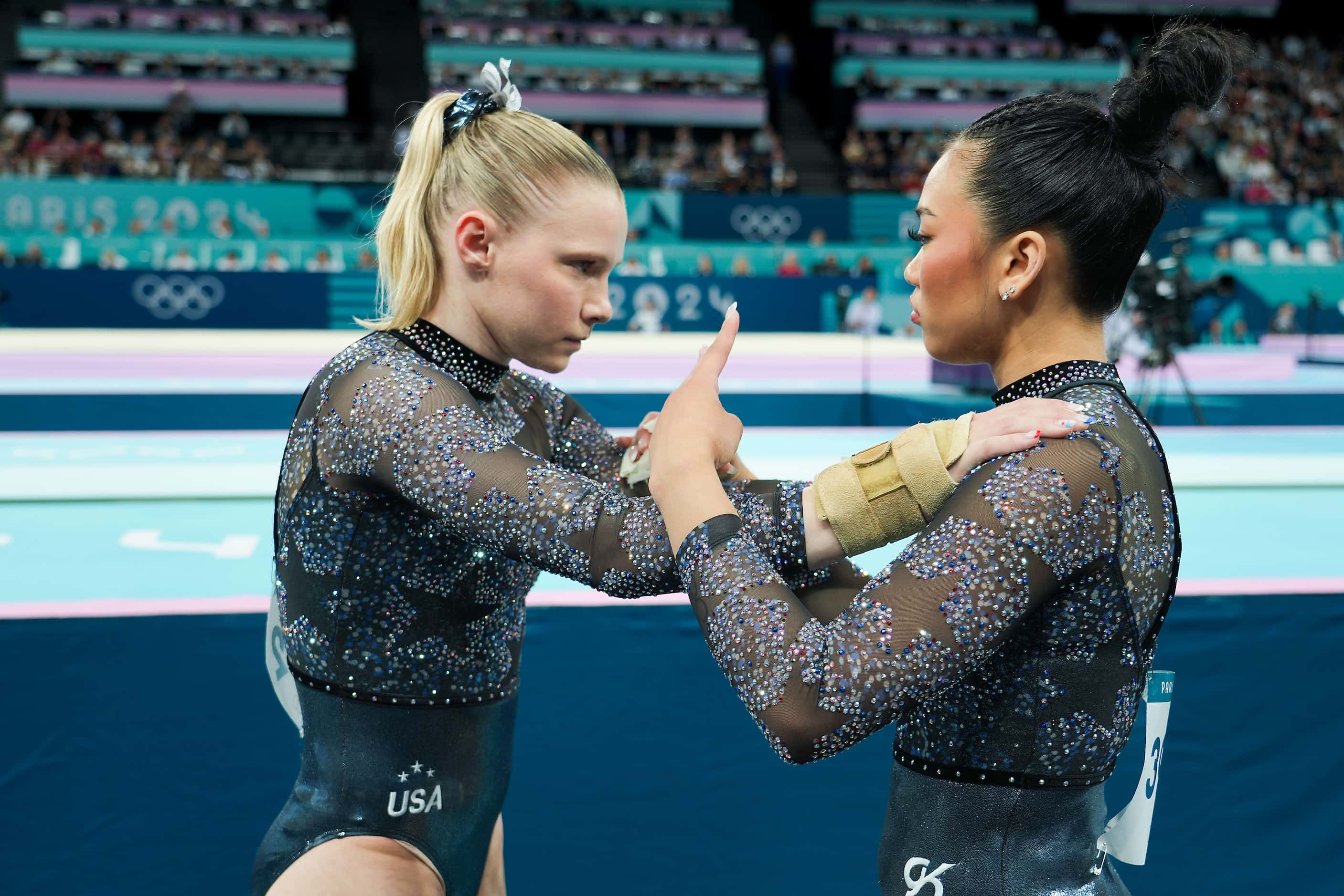 Jade Carey of the United States (left) listens to Suni Lee before competing on the vault...