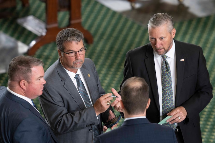 Sens. Charles Perry, R-Lubbock, (holding pen) and Drew Springer, R-Muenster, (right) talked...