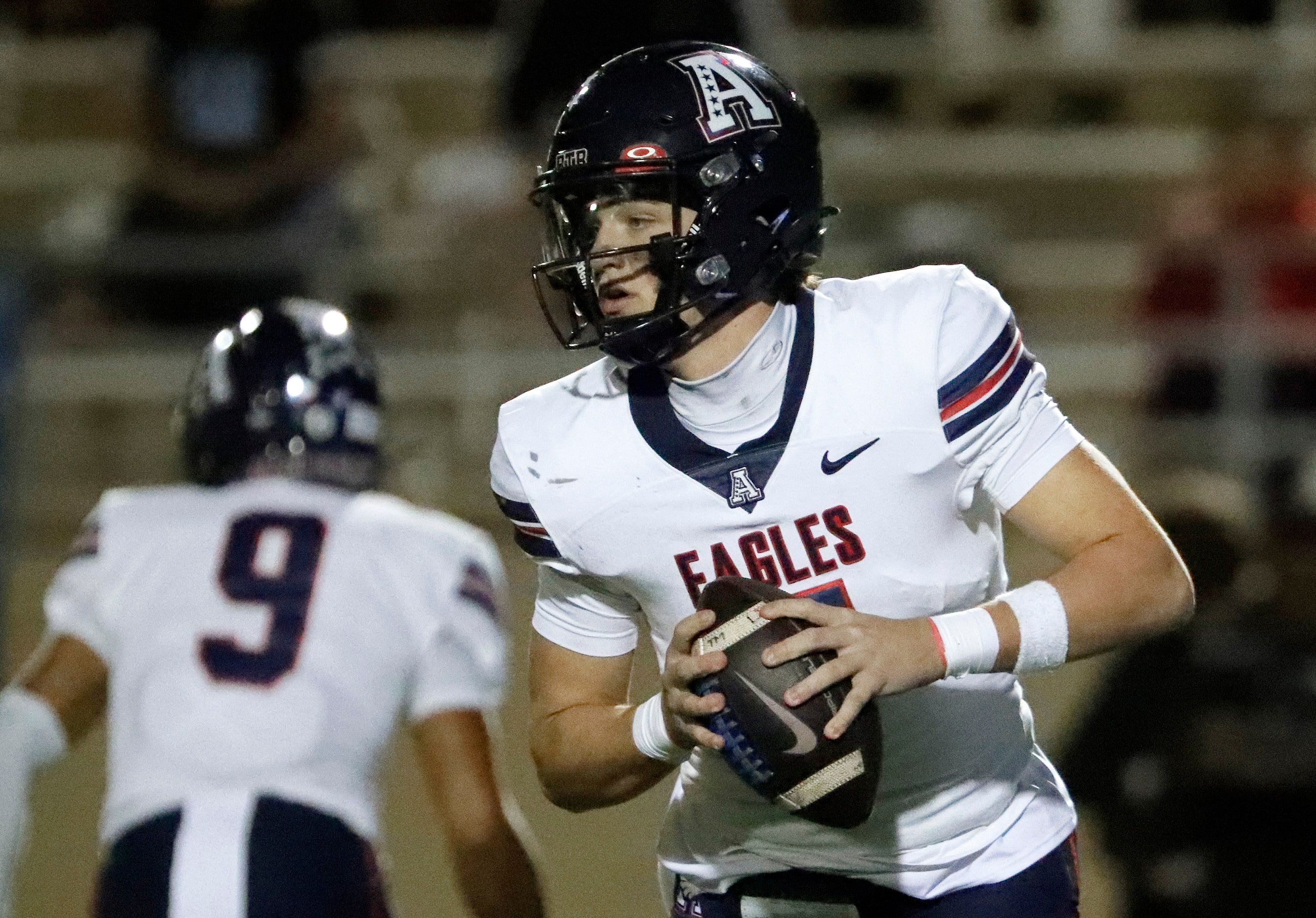 Allen High School quarterback Brady Bricker (7) rolls out before making a throw during the...